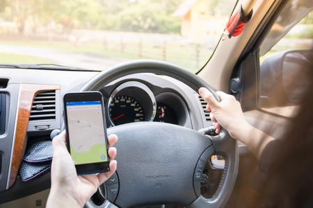 Woman using smart phone to find directions while driving a car.
