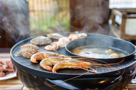 Shrimps and shellfishs grilling on hot pot.