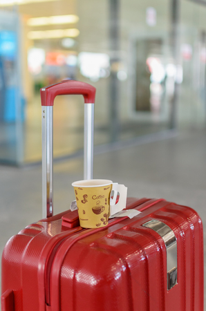 Red baggage with a cup of hot coffeeの写真素材