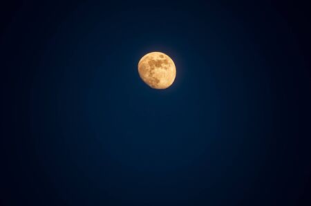 Haft moon or wanning gibbous moon phase with yellow moonlight in deep blue sky background.
