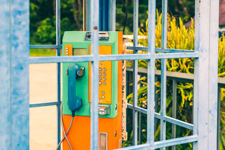 Old and weathered oldstyle plublic pay phone in telephone booth.