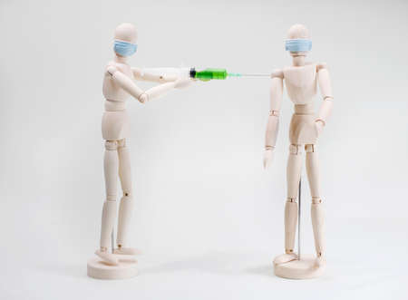 a wooden model of a person vaccinates or injects another person into their shoulder