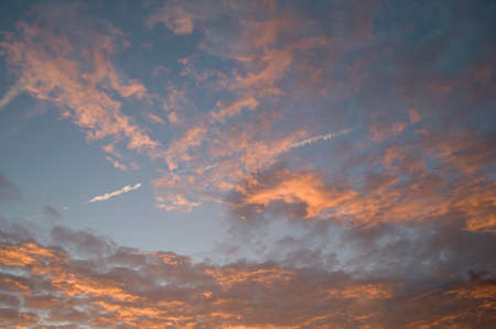 vanilla sunset, gently pink clouds against the background of the sunset sky and the trail of an airplane in the sky, texture,の写真素材