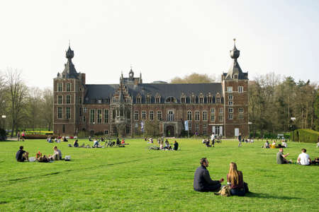 Social distance, students are resting on the lawn near the castle Arenberg Castle, Leuven, Belgium...