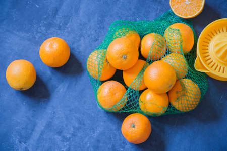 oranges scattered on a blue background for squeezing juice with a manual squeezerの写真素材