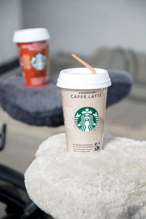 two cups of iced coffee latte and hazelnut macchiato with Starbucks logo stand on the bike seat, As, Belgium, MAY 28, 2021のeditorial素材