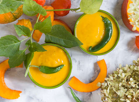 Pumpkin puree soup in green bowls on gray cement background, colorful food,の写真素材