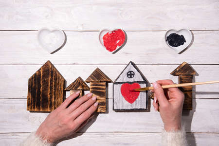female hands draw a heart on a wooden house,step by step diy,crafting Sweet Homeの写真素材