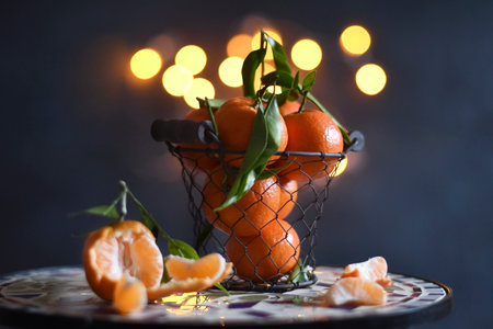 tangerines in a mesh bucket on a table against a background of bright bokehの写真素材