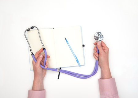 female hands hold a phonendoscope on the background of a notebookの写真素材