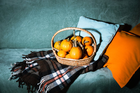 straw basket with pumpkins on the sofa, autumn room decor, Coziness and warmthの写真素材