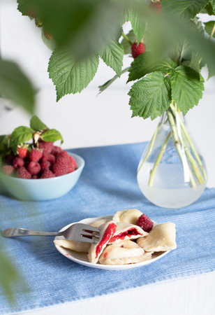 Slavic dish vareniki with fresh raspberries, Still life on a blue backgroundの写真素材