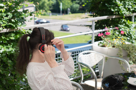 pensive brunette woman listens to music on headphones at a table in a cafe