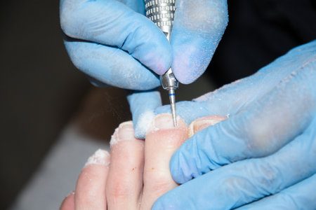 A master in a beauty salon makes a hardware pedicure to a client, soft focusの写真素材
