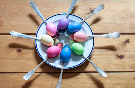 Close-up of colorful Easter eggs in spoons on a wooden backgroundの写真素材