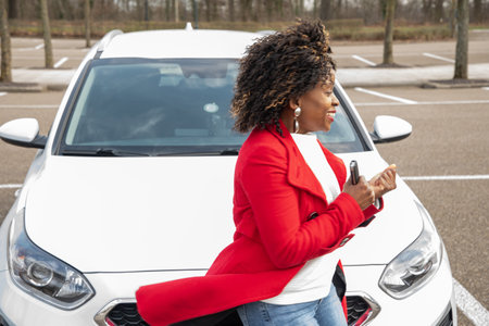 cheerful african american woman goes to car and holding keys, motion blurの写真素材