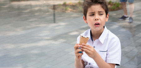 Cute child boy with a dirty face eats ice cream, the child enjoys dessertの写真素材