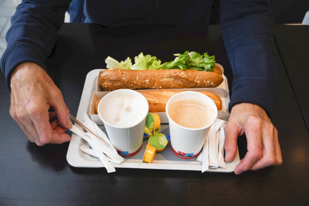 middle-aged man holding a tray with fast food, sandwiches, baguettesの写真素材