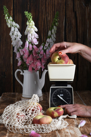 still life with peaches on vintage scales and in string bag,bouquet of foxglovesの写真素材