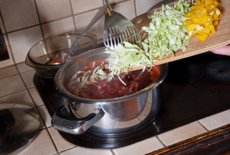 a woman puts cabbage in a saucepan,ingredients for cooking borsch soupの写真素材