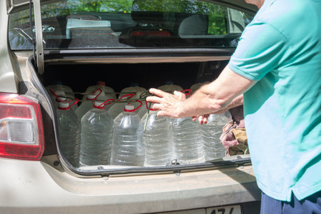 male volunteer loads many five-liter bottles of clean drinking water into the trunk to help victims...