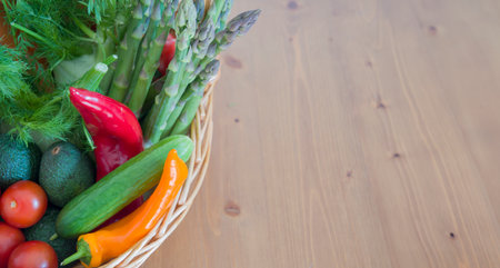 fresh assorted Vegetables in a basket on a wooden table, consumer vegetarian basket, tomatoes, fennel, paprika, asparagus,, cucumbers, avocado, Healthy eating concept, top view, High quality photoの写真素材