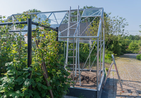 Gardener installs glass on roof of greenhouse in his garden, DIY concept and grow vegetables in small garden plot,の写真素材