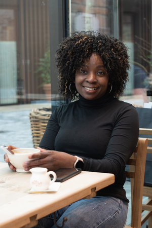 African american woman sits in a cafe in the morning, having just woken up, and drinks coffee, High quality photoの写真素材