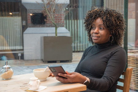 African american woman without makeup talking on smartphone in cafe in the morning, High quality photoの写真素材