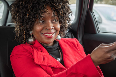 Pretty african woman passenger in a car doing makeup while standing in a traffic jam, concept a modern married business woman with children saves time, High quality photoの写真素材
