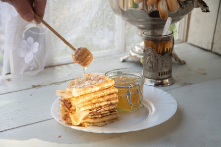 Russian pancakes with honey and a cup of tea from a vintage samovar Maslenitsa festival concept,...