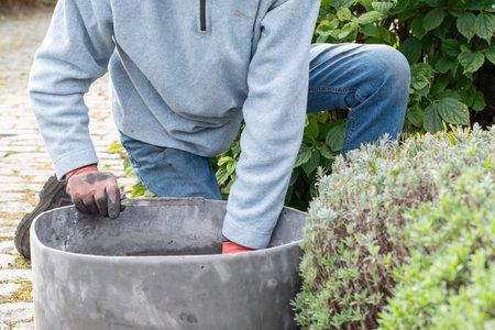 Experienced builder wearing gloves mixes cement mortar in a special container, thoroughly mixing cement, sand and water, ensuring the optimum texture for a strong bond between the bricks,の写真素材