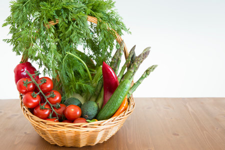 fresh assorted Vegetables in a basket on a wooden table, tomatoes, fennel, paprika, asparagus,cucumbers, avocado, Healthy eating concept, top viewの写真素材