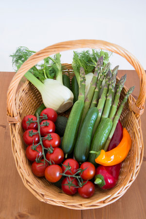 fresh assorted vegetables in a basket on wooden table, tomatoes, fennel, paprika, asparagus,cucumbers, avocado, healthy eating concept, top viewの写真素材