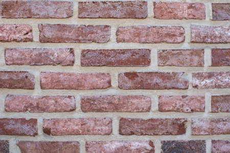 Even rows of red variegated bricks create a classic pattern of stretcher brickwork, an architectural detail for any design project,の写真素材