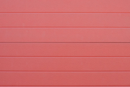 Close up of red corrugated metal sheet creating repeating textured pattern, garage door detail, durable and corrosion resistant cladding material,の写真素材