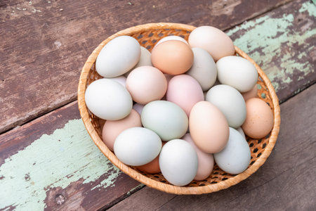 Brown chicken eggs of different shades lie in a wicker basket on a wooden table, creating a rustic still life, a concept of abundance of fresh farm products,の写真素材