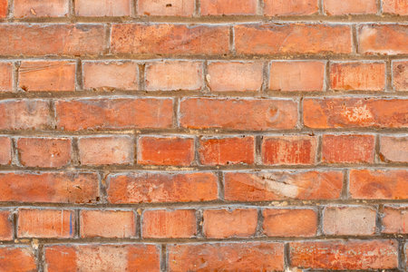 Red brick wall showing signs of age and weathering, with a random pattern, creates a textured and rustic backdrop, giving a sense of history,の写真素材