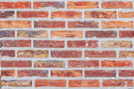 A wall of bricks in different shades of red and brown with repeating pattern of stretcher bricks, attractive textured background in rustic styleの写真素材