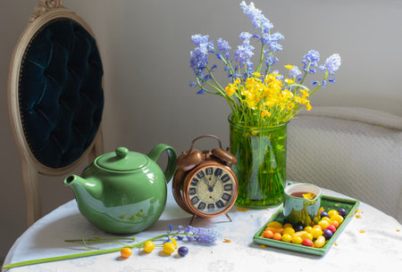 Still life composition featuring a bright green teapot, a classic alarm clock, and a vibrant bouquet...