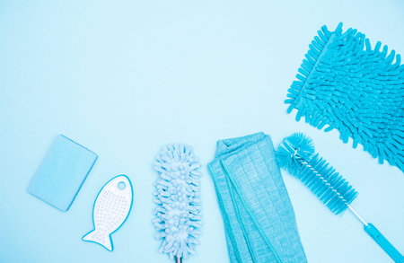 Monochrome blue flat lay composition featuring set of cleaning supplies including a dust brush,...