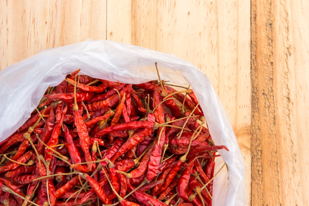 Dried chillies in a white plastic bag placed on a wooden floor.の写真素材