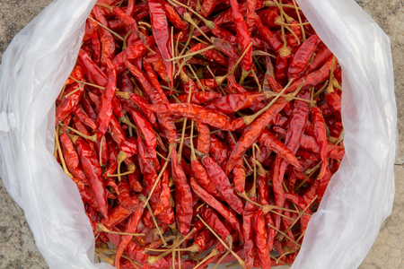 Dried chillies in white plastic bags placed on concrete floorの写真素材