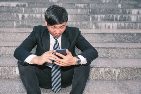 Asian businessmen with headaches or migraines at the city hall after work Images of young businessmen who are tired, stress, crisis, depression, failure in business conceptsの写真素材