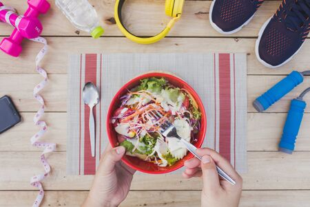 Young woman eating fruit salad together with fitness equipment.の写真素材