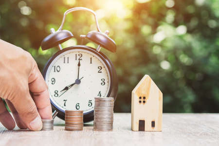 Close-up, money house and clock model with green bokeh background, money saving concept to prepare for the future.の写真素材