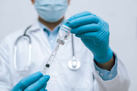 Doctor, nurse, scientist hand in blue gloves holding flu, measles, coronavirus, covid-19 vaccine disease preparing vaccination shot, medicine and drug concept.の写真素材