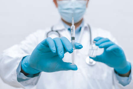 Doctor, nurse, scientist hand in blue gloves holding flu, measles, coronavirus, covid-19 vaccine disease preparing vaccination shot, medicine and drug concept.の写真素材