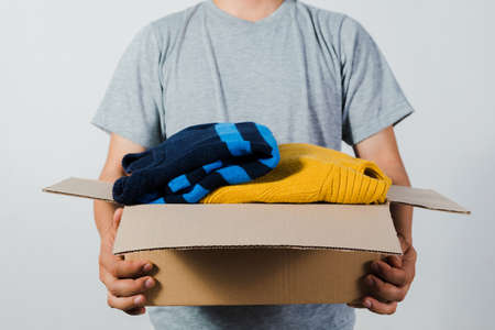 man holding a crate of second-hand clothes unused clothes