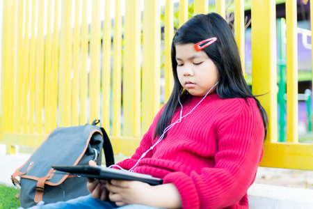 Asian girl watching a table on the school lawnの写真素材